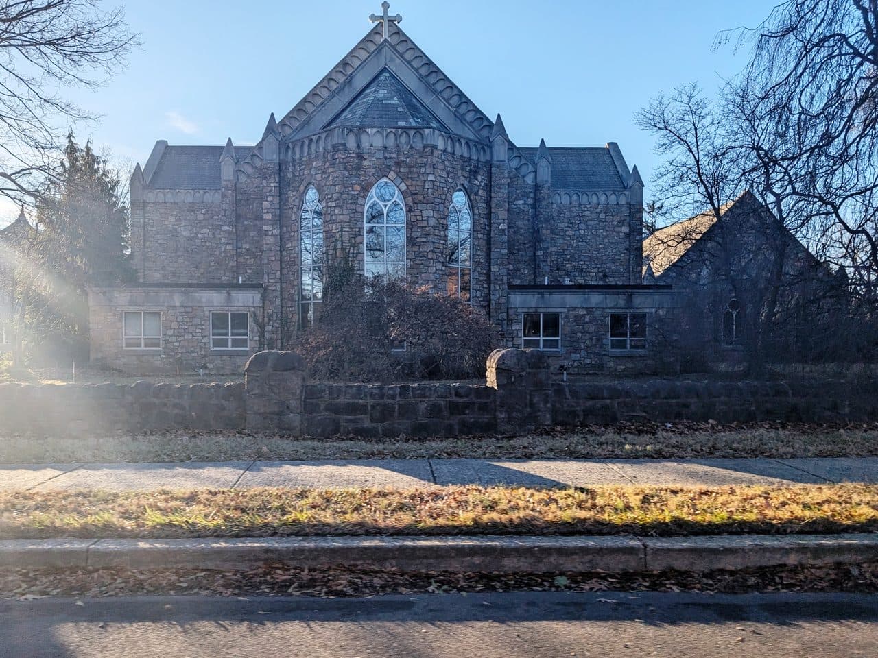 Trinity Episcopal Church in Ambler, Pennsylvania, a stone gothic church with a steep gabled roof and a tall arched window.