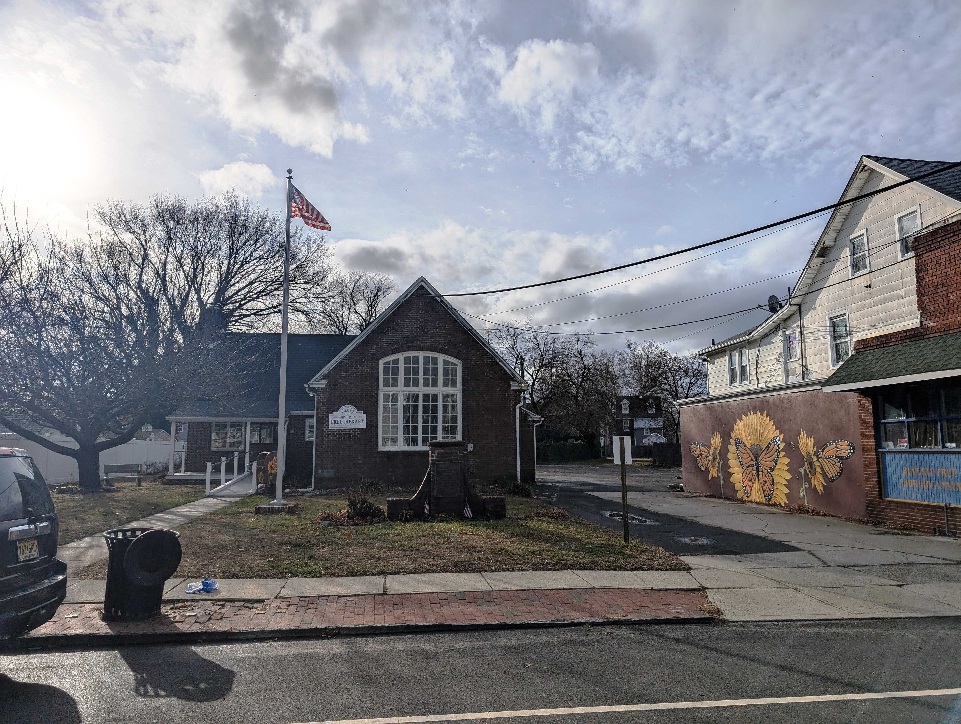 The Beverly Free Library, a small brick building with a gabled entrance, on a residential street in Beverly, New Jersey.
