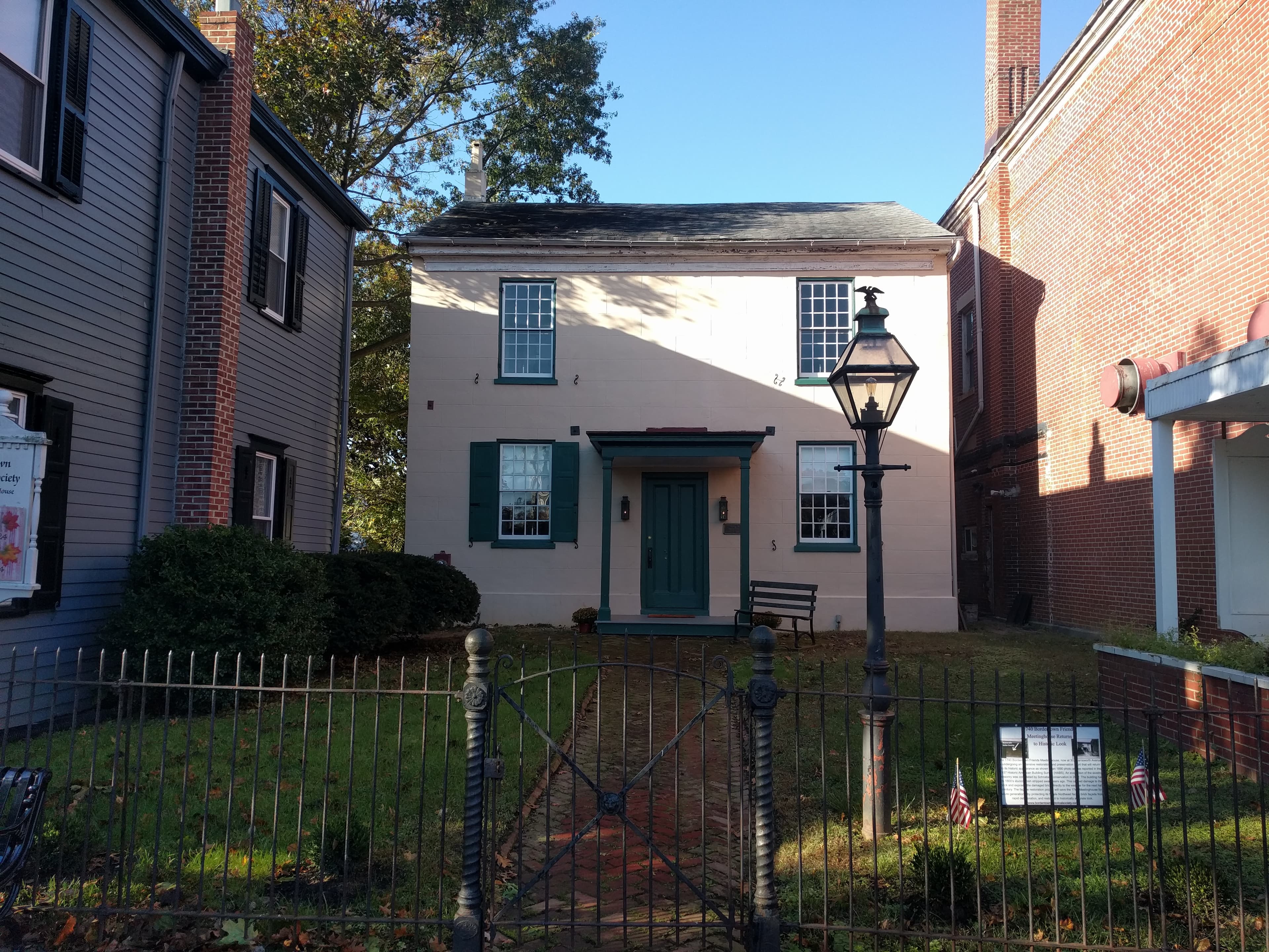 The Bordentown Friends Meetinghouse, a plain two-storey brick building with shuttered windows, set behind a low wall in Bordentown, New Jersey.