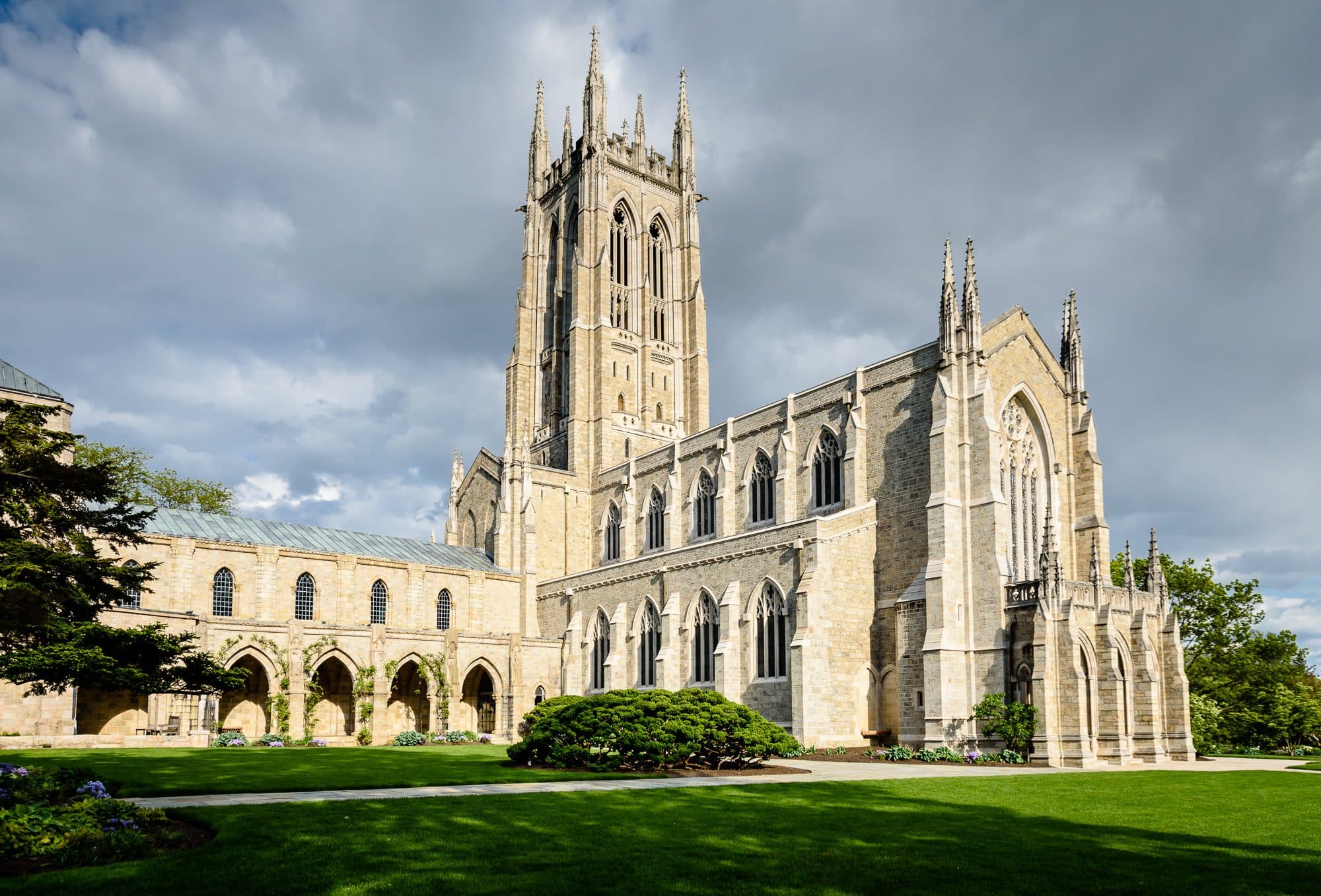 Bryn Athyn Cathedral in Pennsylvania — a pale stone Gothic church with a tall square tower and pinnacles, seen across its lawn and cloister.