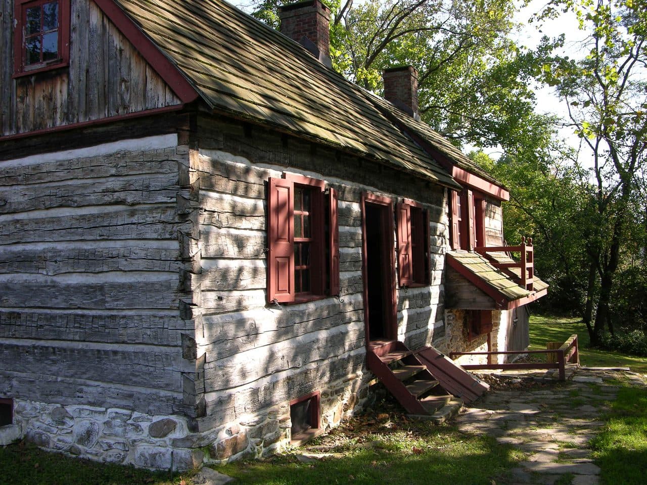 The Moon-Williamson House in Historic Fallsington, a whitewashed log dwelling with red shutters and a shingled roof, in Falls Township, Pennsylvania.