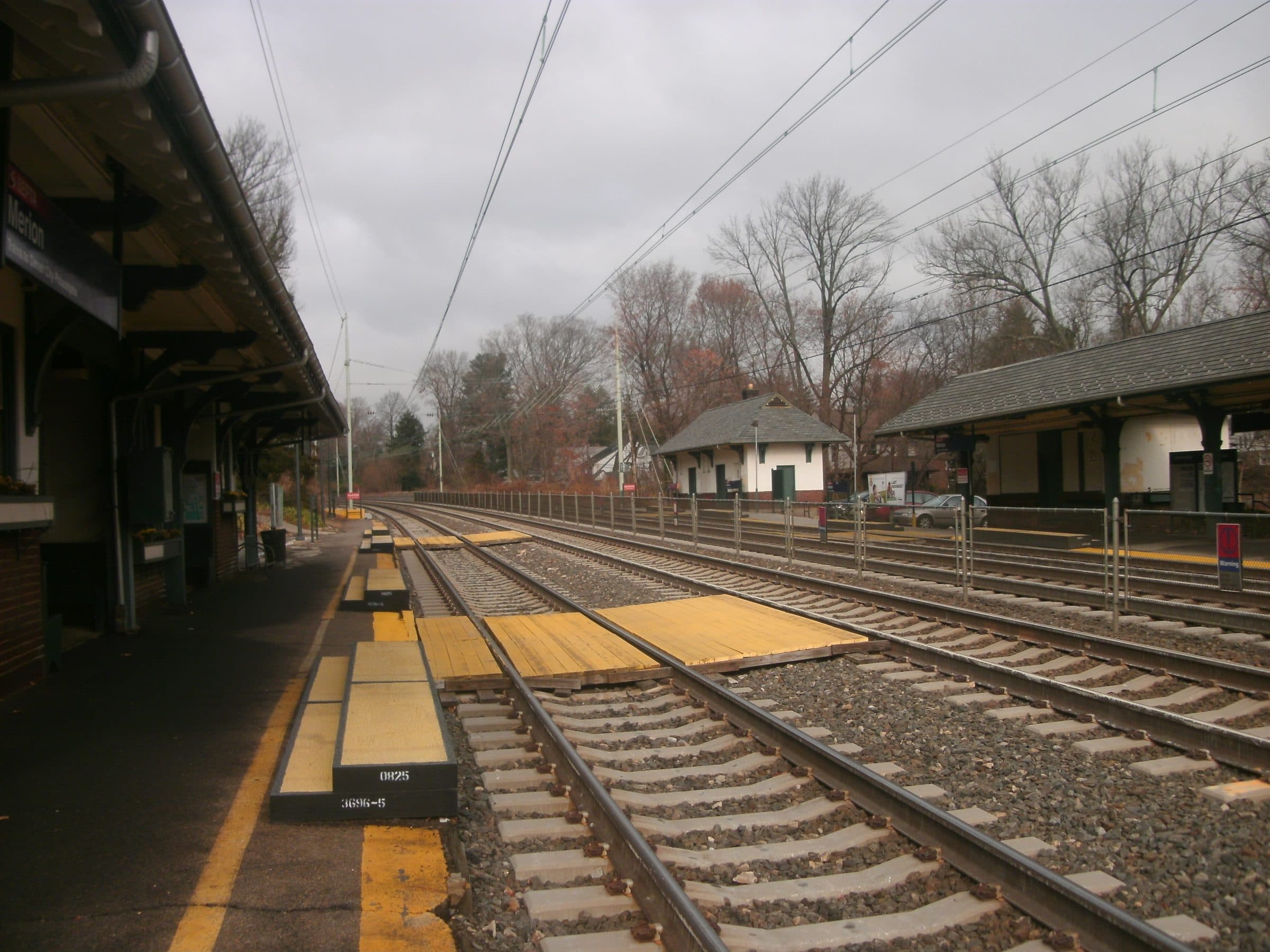 Merion station in Pennsylvania on a gray winter day — the platform canopy and SEPTA sign reading Merion, with the tracks running toward the outbound shelter.