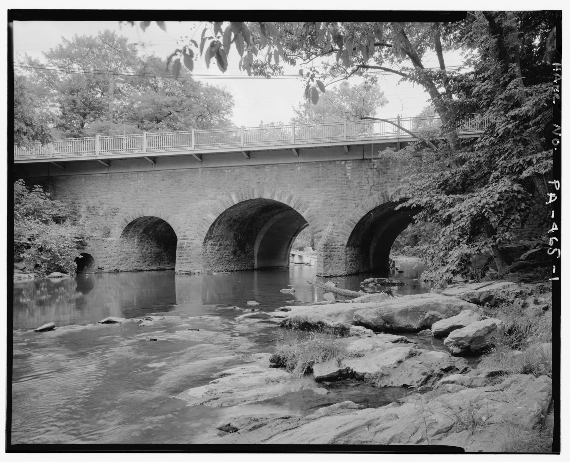 The 1697 Pennypack Creek bridge carrying Frankford Avenue in the Holmesburg section of Philadelphia — three low stone arches over the creek, the oldest road bridge still in use in the United States.