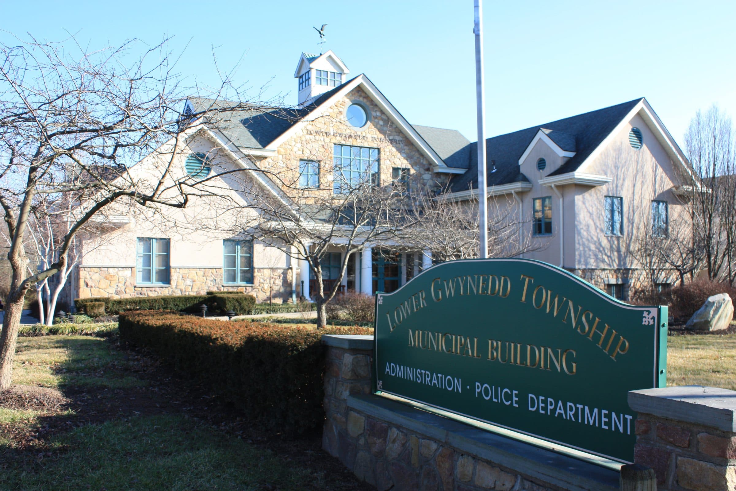 The Lower Gwynedd Township municipal building at Spring House, Pennsylvania — a fieldstone and stucco building with a cupola, behind a green sign reading Lower Gwynedd Township Municipal Building.