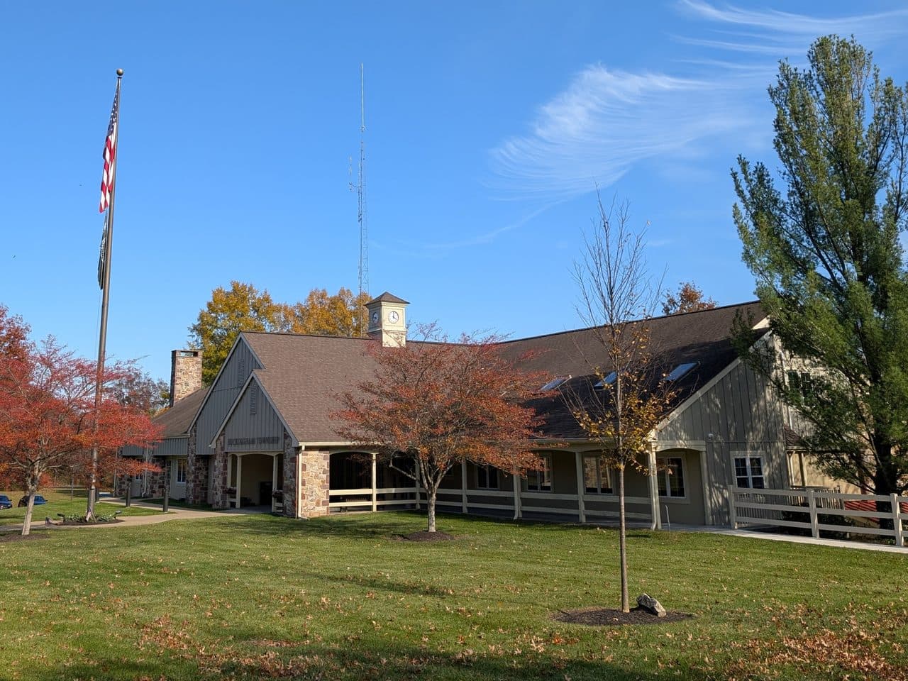 The Buckingham Township municipal building in Bucks County, Pennsylvania, a low stone and timber building with a cupola, seen from the road in autumn.