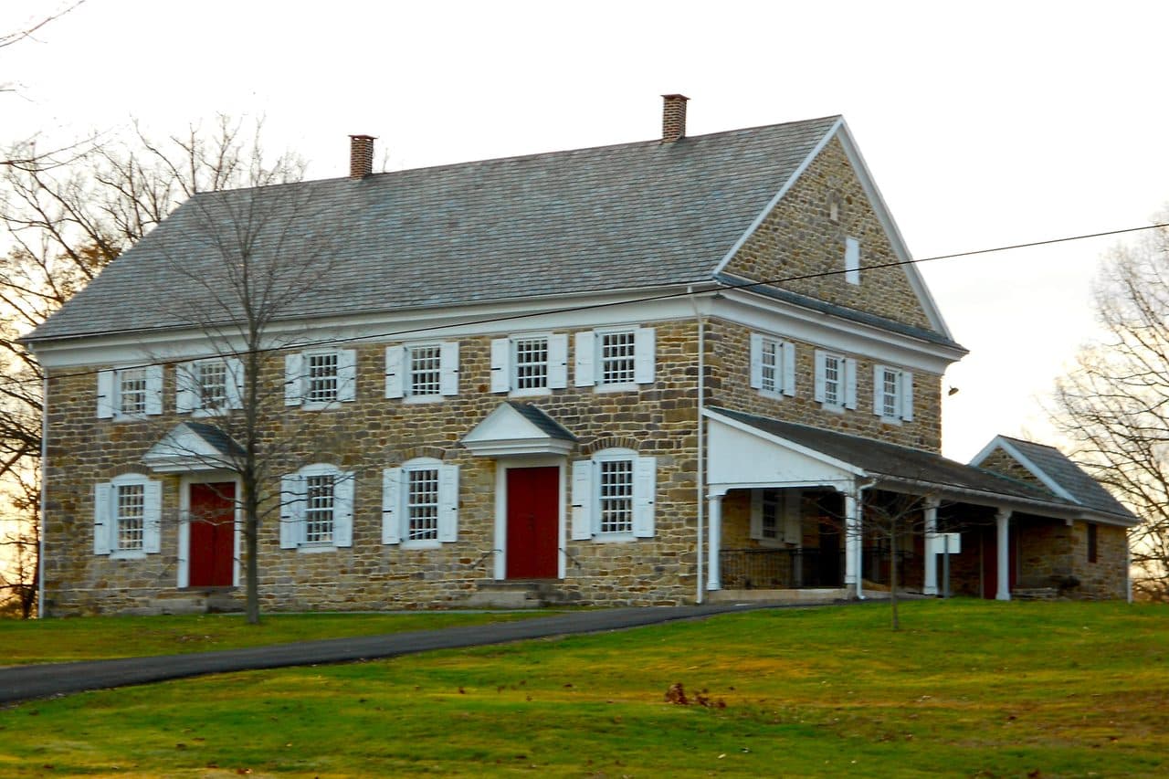 Buckingham Friends Meeting in Buckingham Township, Bucks County, a long fieldstone meetinghouse with white shutters and red doors.