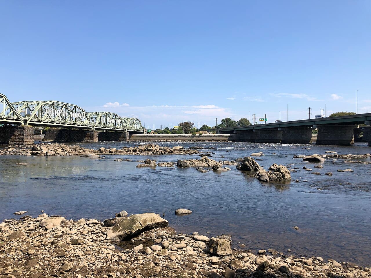 The Delaware River at low tide seen from the Morrisville, Pennsylvania bank, with the Lower Trenton Bridge and its "Trenton Makes, The World Takes" sign crossing to New Jersey.