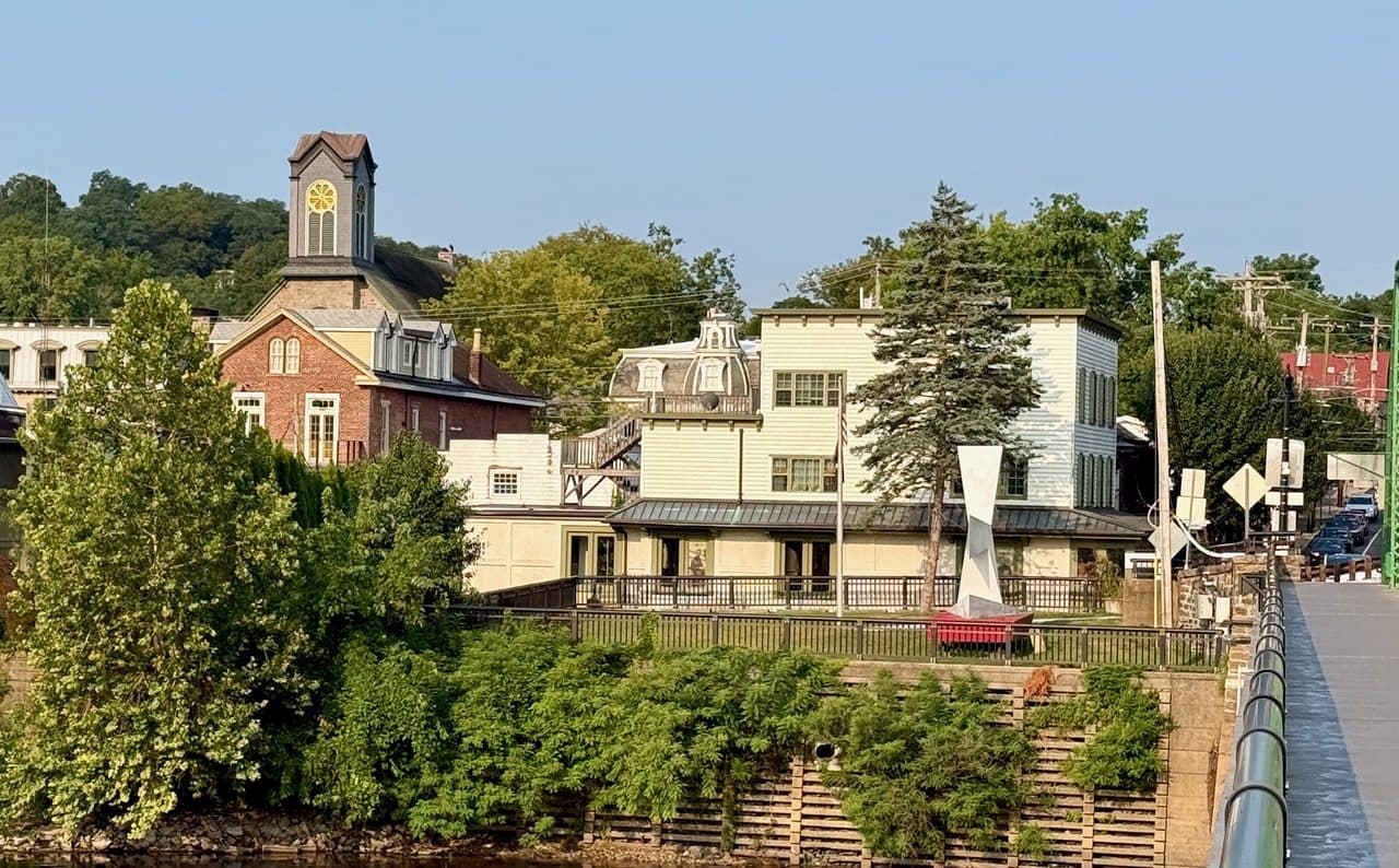 The riverfront at New Hope, Pennsylvania seen from the Delaware River bridge, with the clock tower, brick and clapboard buildings above the water.