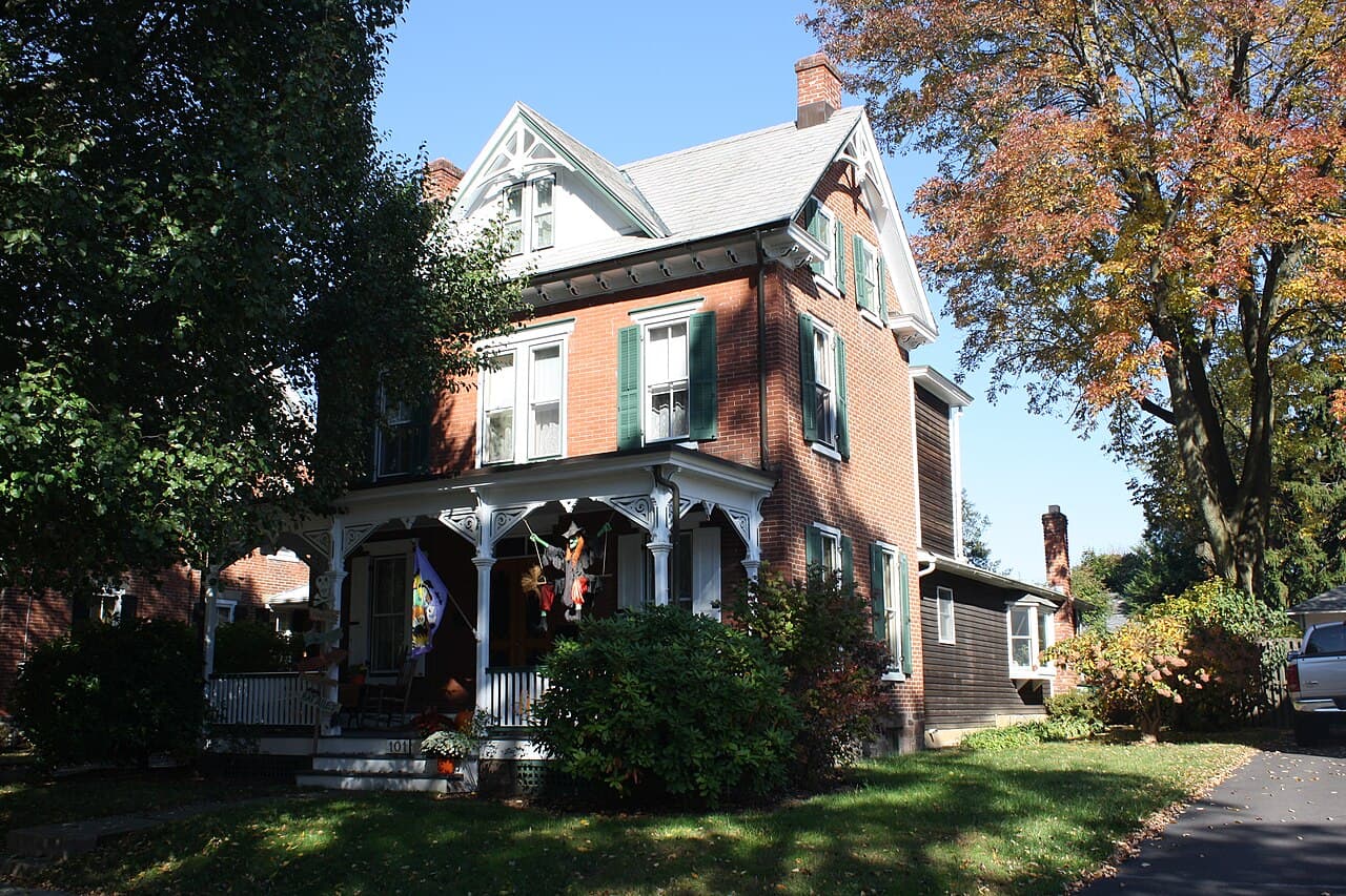 A brick Victorian house with a covered porch and green shutters in the Newtown Historic District, Newtown, Bucks County, Pennsylvania.