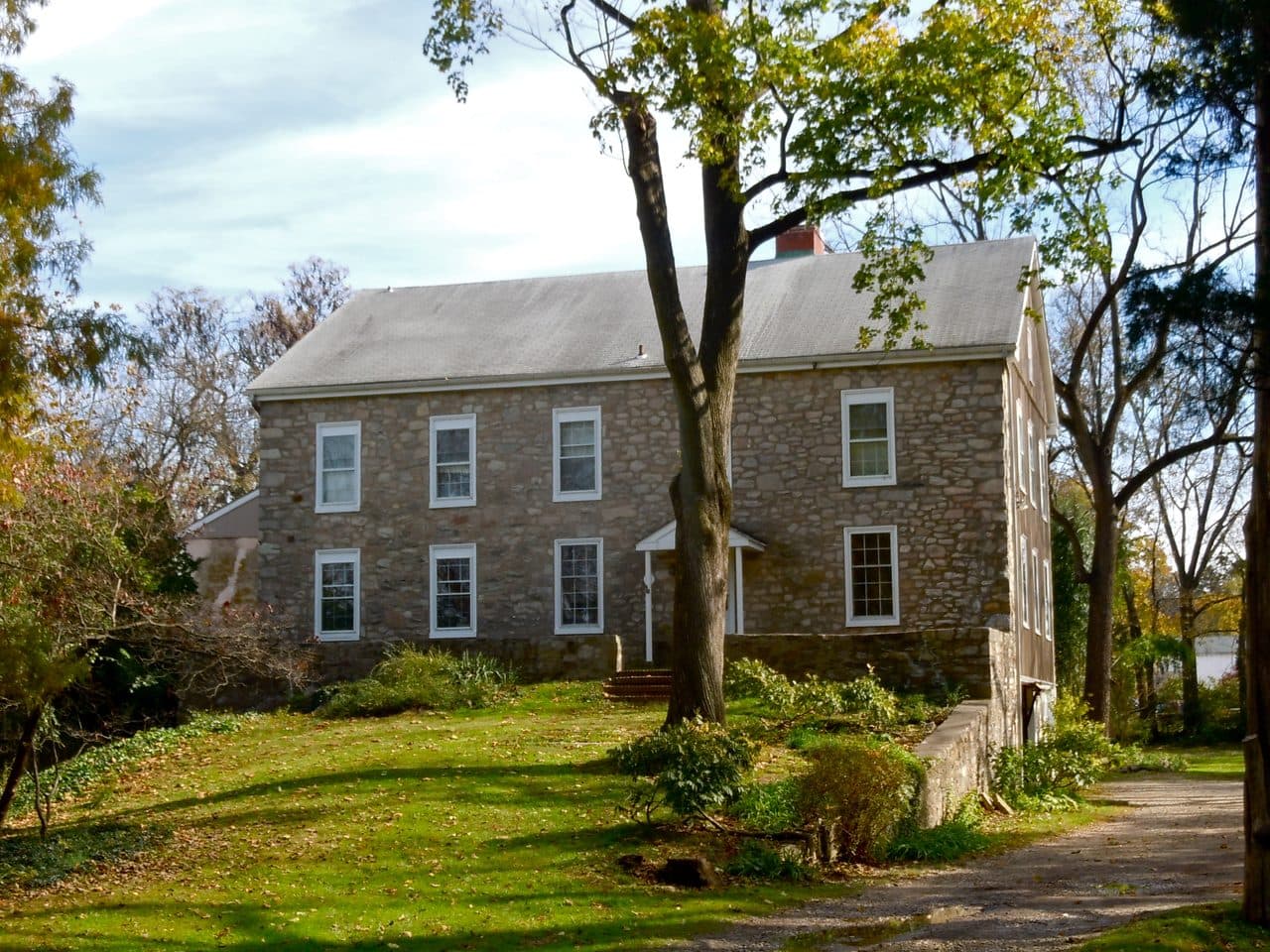 Abolition Hall at Plymouth Meeting, Pennsylvania, a two-story fieldstone building among mature trees on a sloping lawn.